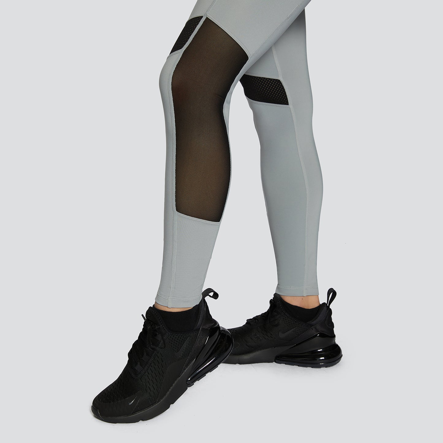 Woman wearing grey and black mesh workout unitard during a Pilates session